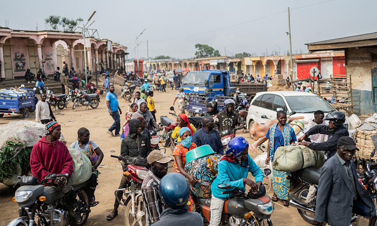 Motorcycle taxi riders and their passengers wait at the entrance to the central market while sanitation workers disinfect the area, as Ituri province continues to combat an Ebola outbreak in Bunia, Congo, on May 23, 2026. Photo: VCG
