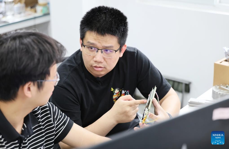 Fu Mingda (R) talks with his colleague at Galileo (Tianjin) Technology Co., Ltd. in Tianjin, north China, May 22, 2026. Thirty-three-year-old Fu Mingda, an electromagnetic engineering designer at Galileo (Tianjin) Technology Co., Ltd., has his sights set on becoming a technical expert in the motor industry. To that end, he has been tackling key challenges in the independent research and development (R&D) of core robotic components.
After earning his master's degree from Shenyang University of Technology in 2018, Fu relocated to Tianjin to focus on the R&D and design of aviation motors. He later joined Galileo, where he was involved in the in-house development of quadruped robot joint modules from the ground up.
At the time, the company relied on externally procured joint modules that were prone to overheating and damage. Furthermore, these outsourced parts could not meet complex performance requirements, such as performing somersaults, climbing slopes, and carrying heavy loads.
In less than six months, Fu achieved a technological breakthrough. Overseeing the process from initial electromagnetic design to supplier development, assembly, and testing, he drove the project through four major iterations and dozens of minor optimizations. Impressively, the very first prototype reached advanced standards in the industry.
Today, fueled by the rapid growth of China's domestic robotics industry, Fu remains busier than ever. He expressed full confidence that, through continued dedication, he will realize his ambition of becoming a leading technical expert in the motor sector. Photo: Xinhua