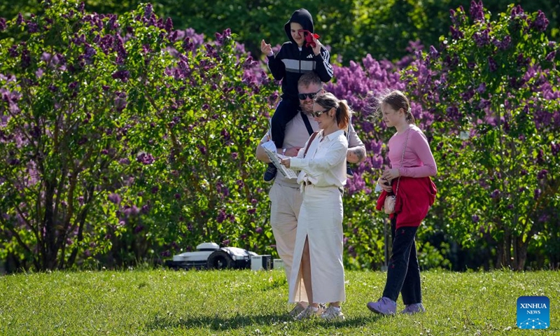 People enjoy their leisure time at a park with blooming lilac flowers in Dobele, Latvia, May 24, 2026. (Photo by Edijs Palens/Xinhua)