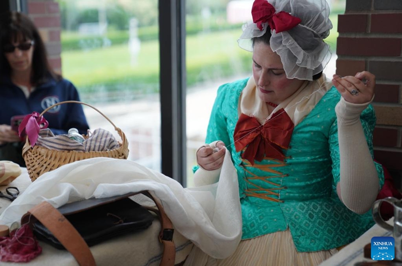 A woman in costumes makes clothes during the Re-enactment Village event in Long Island of New York, the United States, on May 23, 2026. An event titled the Re-enactment Village kicked off in New York on Saturday to recreate the daily life of 18th-century. (Xinhua/Zhang Fengguo)