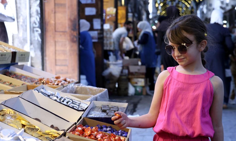 A girl shops for sweets ahead of the Muslim festival of Eid al-Adha, or the Feast of Sacrifice, in Damascus, Syria, May 24, 2026. (Photo by Ammar Safarjalani/Xinhua)