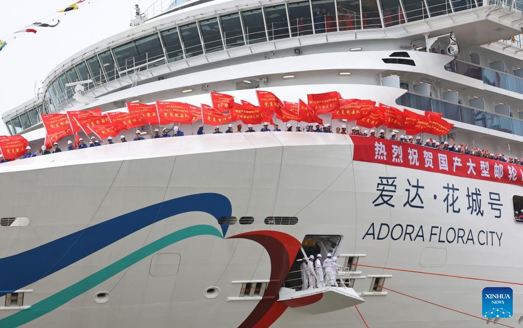 Technicians wave flags to the welcoming crowd on the cruise ship Adora Flora City berthing at a port in east China's Shanghai, May 27, 2026. China's second domestically built large cruise ship, the Adora Flora City, returned to port in Shanghai on Wednesday after completing a 12-day maiden sea trial, marking a milestone in the country's push to mass-produce large cruise ships. The ship is scheduled for delivery on November 6 and will operate international routes from the Nansha International Cruise Home Port in Guangzhou, capital of south China's Guangdong Province. (Photo: Xinhua)