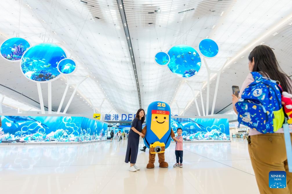 Passengers pose for photos with a mascot at the departures hall of Terminal 2 of Hong Kong International Airport in south China's Hong Kong, on May 27, 2026. Hong Kong International Airport's expanded Terminal 2 departures hall was officially put into operation on Wednesday following a 12.9 billion-Hong Kong-dollar upgrade. (Photo: Xinhua)