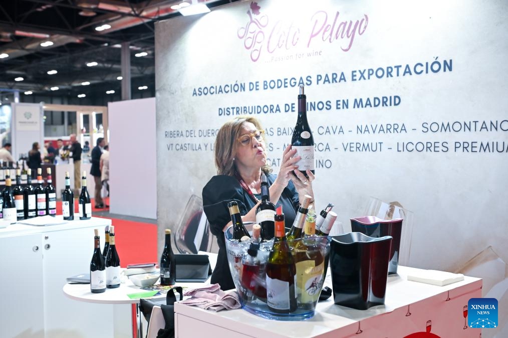 A woman tries to read the label of a wine bottle during the Madrid International Wine Fair (WINEMAD) in Madrid, Spain, May 27, 2026. The fair opened here on Wednesday and will last till Friday. (Photo: Xinhua)