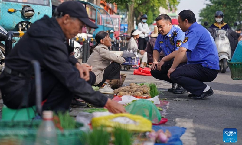 Market managers get to know about the business of farmers at a roadside tidal market in Chaisang District of Jiujiang, east China's Jiangxi Province, May 12, 2026. Chaisang District in Jiujiang has found a clever way to tackle the classic conflict between street vendors and morning commuters by launching a flexible tidal market system. Under the system, vendors can use specific roadside areas from 6 a.m. to 8 a.m. without paying any charge, while keeping the streets clear for regular traffic during rush hours. (Photo: Xinhua)