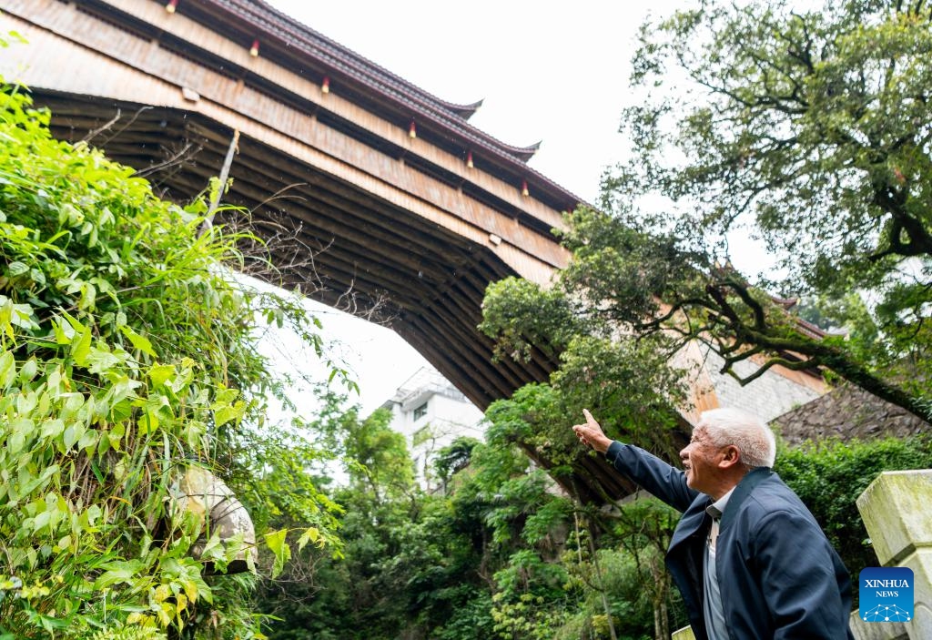 Wu Zongshan, an inheritor of building wooden-roofed arch bridges, introduces the Qifeng Bridge, a contemporary wooden-roofed arch bridge he assisted in building, in southeast China's Fujian Province, May 13, 2026. The wooden-roofed arch bridge is an ancient and unique structure characterized by a corridor built atop a bridge spanning a river. It reflects the craftsmanship of ancient builders who joined wood into an arch without using nails or metal parts. (Photo: Xinhua)