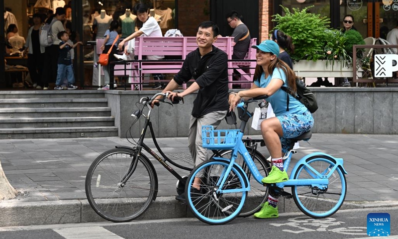 Liu Lichao (L) cycles with an American tourist along the Wukang Road in east China's Shanghai, May 23, 2026. As the China Travel hashtag goes viral across global social media platforms, China has witnessed a sustained boom in inbound tourism, with Shanghai as the first leg. Liu Lichao discovered something unexpected while cycling with his overseas clients when he still worked in the financial sector. People from different cultural backgrounds tend to relax naturally during cycling, which makes communication more easily. (Photo: Xinhua)