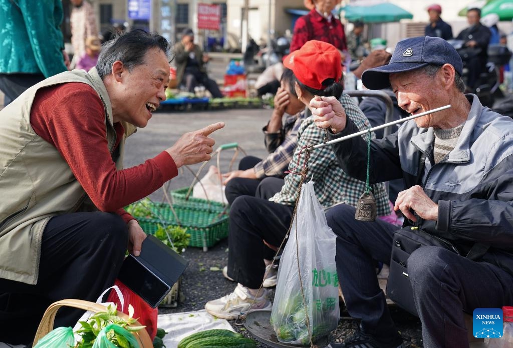 A resident buys vegetables from a farmer at a roadside tidal market in Chaisang District of Jiujiang, east China's Jiangxi Province, May 12, 2026. Chaisang District in Jiujiang has found a clever way to tackle the classic conflict between street vendors and morning commuters by launching a flexible tidal market system. Under the system, vendors can use specific roadside areas from 6 a.m. to 8 a.m. without paying any charge, while keeping the streets clear for regular traffic during rush hours. (Photo: Xinhua)