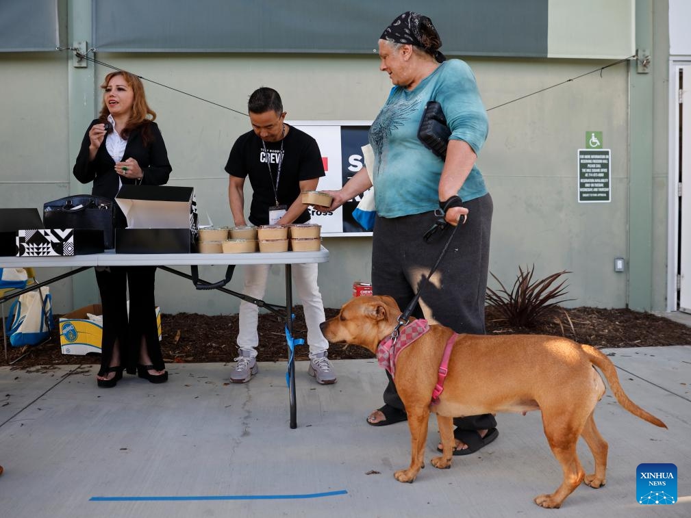 An evacuee with her pet receives food at the entrance to an emergency shelter in Fountain Valley, Orange County, California, the United States, on May 24, 2026. California authorities said on Sunday that a potential crack was found in a damaged industrial tank containing volatile chemicals in Orange County as emergency crews raced to prevent the tank from rupturing or exploding. (Photo: Xinhua)