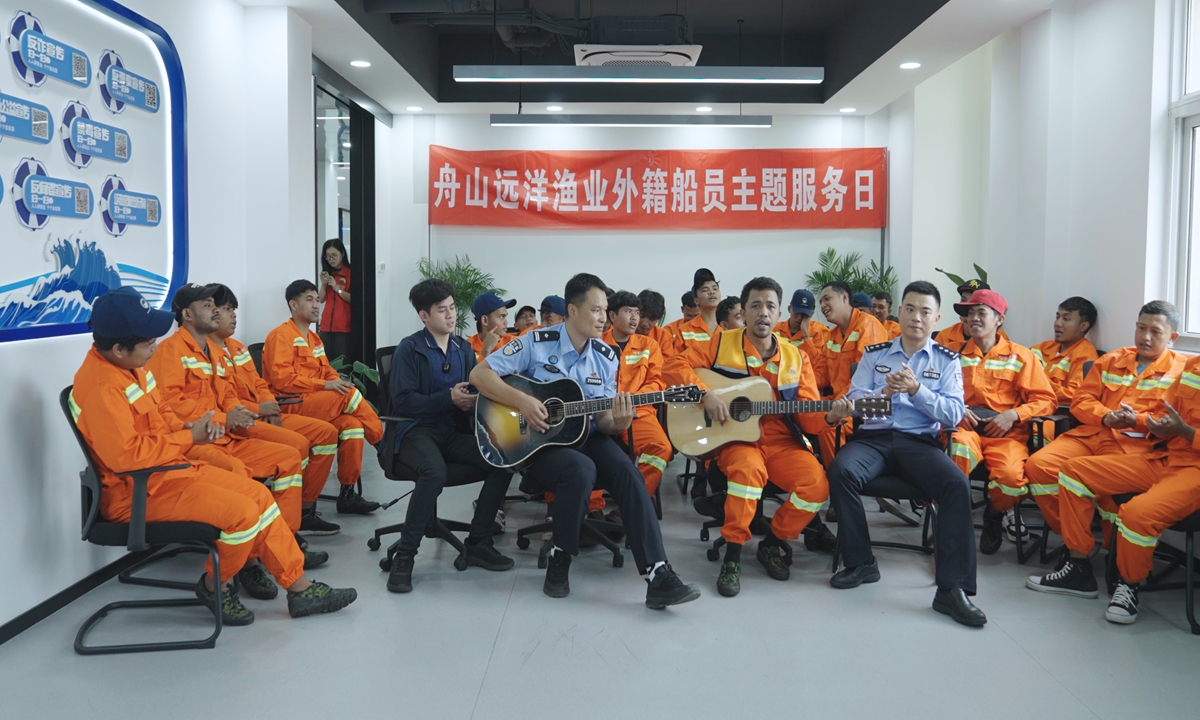 An Indonesian crew member plays guitar as fellow crew members sing along with Chinese immigration officers at Zhoushan National Distant-Water Fishing Base on May 14, 2026. Photo: Courtesy of Shanghai Ocean University