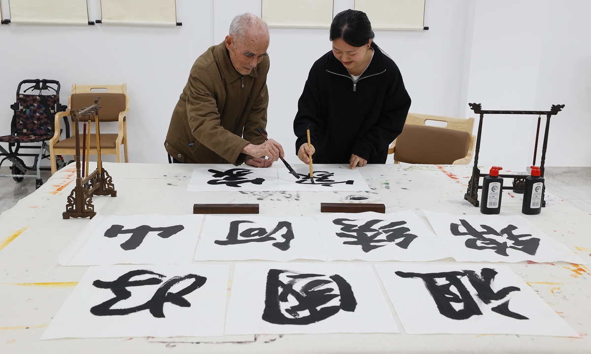 A young person born in the 2000s practices calligraphy with one of her elderly co-residents in the center on October 23, 2025. Photo: VCG