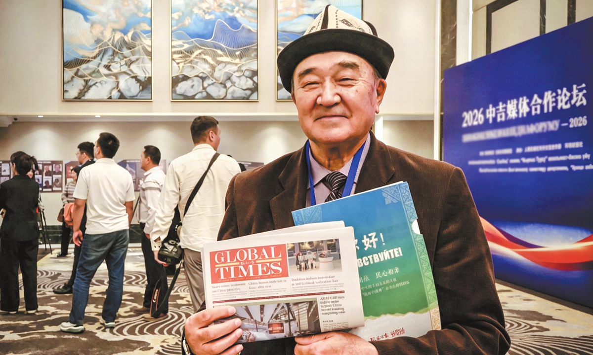 A guest displays the Global Times newspaper (English edition) and cultural and creative products at the venue of the 