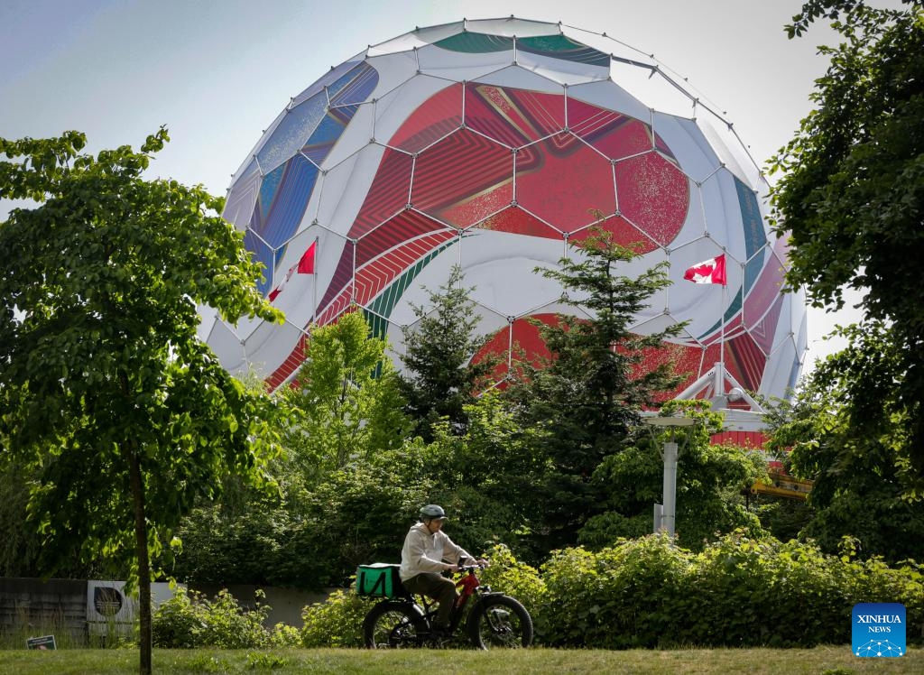 A person rides past the dome of Science World as it is being transformed into a giant official match ball of the FIFA World Cup 2026 ahead of the tournament in Vancouver, British Columbia, Canada, on May 29, 2026. (Photo: Xinhua)