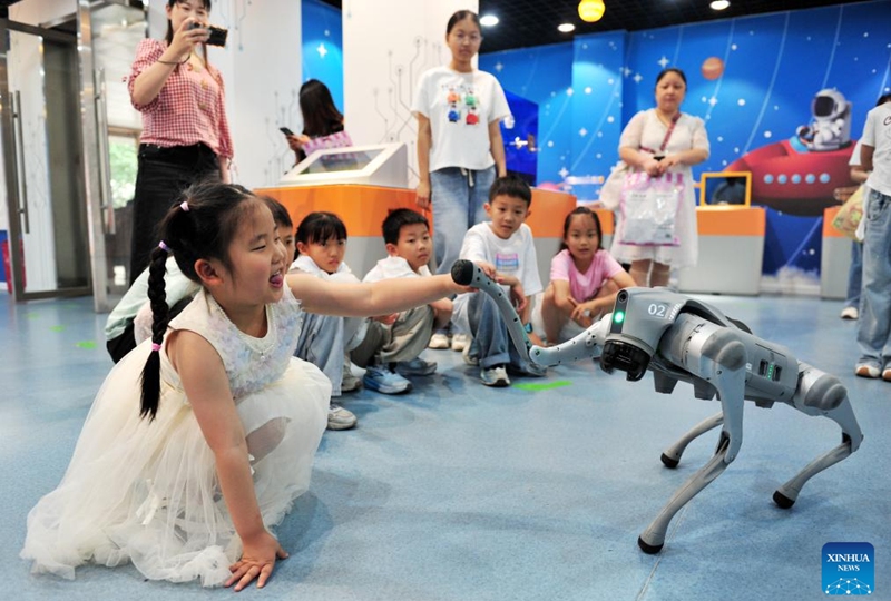 A girl interacts with a robot dog at a science and technology hall in Zigui County, Yichang City of central China's Hubei Province, May 30, 2026. Various events are held across the country to celebrate the upcoming International Children's Day. (Photo by Wang Huifu/Xinhua)