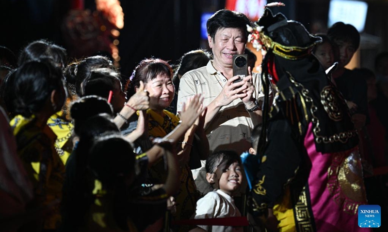 People interact with a performer at a tourist attraction in Baoting, south China's Hainan Province, May 29, 2026. Rooted in the distinctive traditions of the Li and Miao ethnic groups, the tourist attraction features immersive night tour experiences as its core draw. (Xinhua/Pu Xiaoxu)