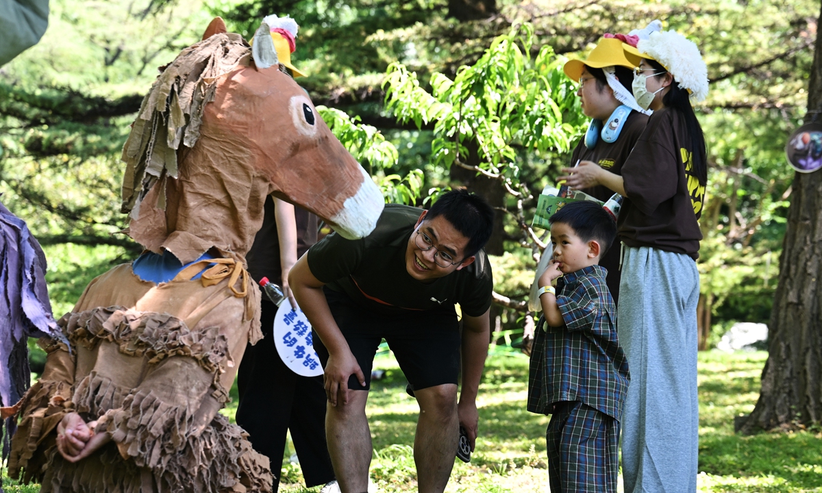 A child interacts with a performer in a handmade paper costume at an animal-themed party celebrating International Children's Day at the Beijing Zoo on June 1, 2026. Photo: VCG