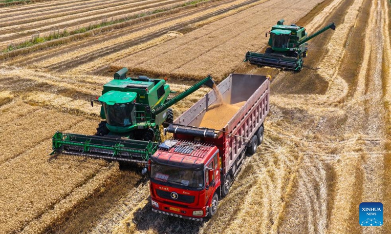 This aerial drone photo taken on May 31, 2026 shows harvesters in a wheat field in Xuyi County, east China's Jiangsu Province. (Photo by Xu Changyin/Xinhua)