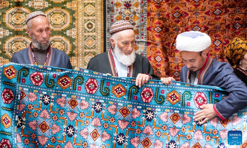 An exhibitor (R) displays a carpet at an exhibition on the Turkmen Carpet Day in Ashgabat, Turkmenistan, May 31, 2026. (Photo by Cui Jiaxin/Xinhua)