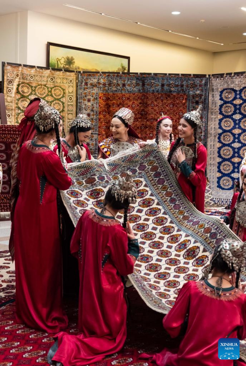 Actresses display a carpet at an exhibition on the Turkmen Carpet Day in Ashgabat, Turkmenistan, May 31, 2026. (Photo by Cui Jiaxin/Xinhua)