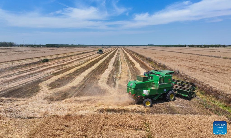 This aerial drone photo taken on May 31, 2026 shows harvesters in a wheat field in Xuyi County, east China's Jiangsu Province. (Xinhua/Ji Chunpeng)