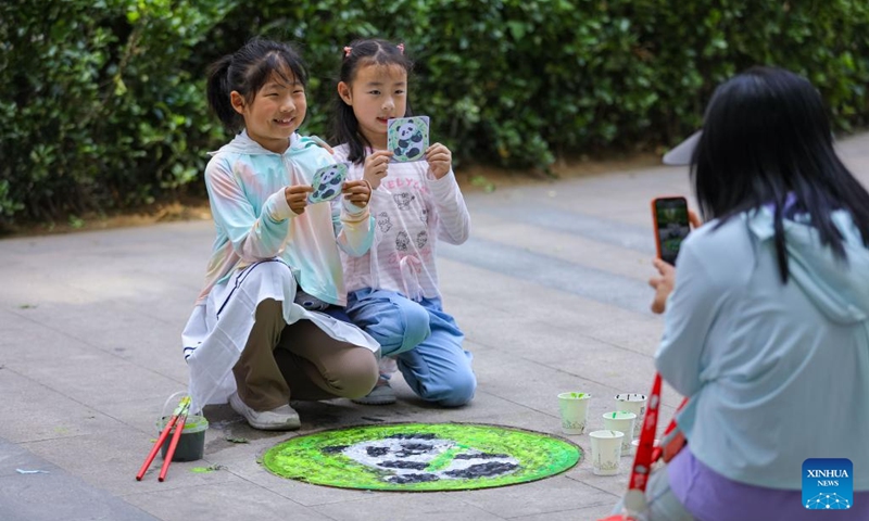 Children pose for photos in front of a manhole cover with a hand-drawn panda pattern at Licang District of Qingdao City, east China's Shandong Province, May 31, 2026. Various events were held across the country on Sunday to celebrate the upcoming International Children's Day. (Photo by Zhang Ying/Xinhua)