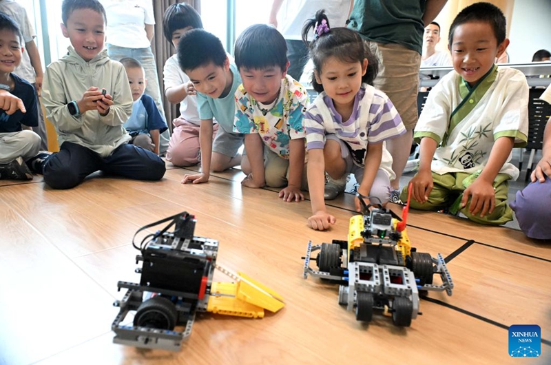 Children interact with robots at the Shijiazhuang Library in Shijiazhuang, north China's Hebei Province, May 31, 2026. Various events were held across the country on Sunday to celebrate the upcoming International Children's Day. (Photo by Chen Qibao/Xinhua)