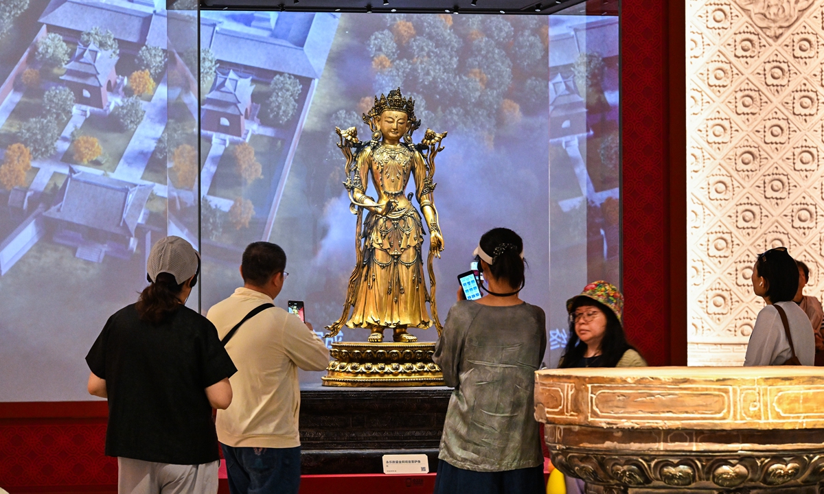 Visitors examine a gilt bronze statue of the Avalokitesvara Bodhisattva, or Guanyin, made during the reign of Emperor Yongle of the Ming Dynasty (1368-1644), at an exhibition in Beijing on June 2, 2026.