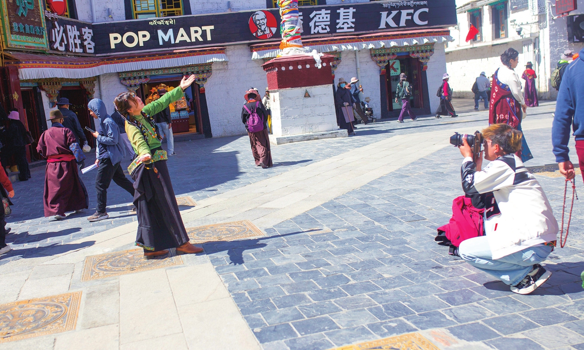 A tourist dressed in Tibetan clothing poses for photos on Barkhor Street, Lhasa, Southwest China's Xizang Autonomous Region on May 22, 2026. 