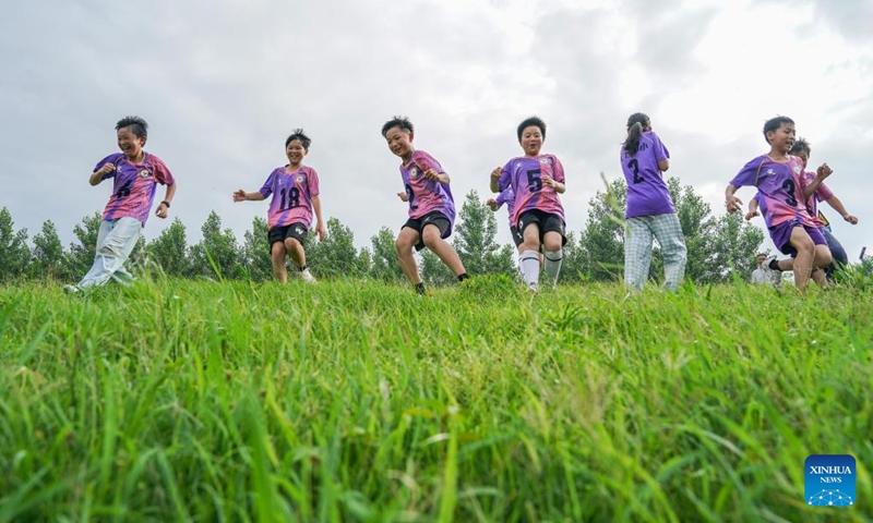 Children sprint on a slope near the Tongma dike of Yangtze River during a football training session in Susong County of Anqing, east China's Anhui Province, May 26, 2026. Nestled at the junction of Anhui, Hubei and Jiangxi provinces, Huikou Town in Susong County of Anqing, east China's Anhui Province, is the first riverside town greeted by the Yangtze River as it flows into Anhui. Stretching alongside the town is the Tongma dike, a flood barrier that shields the riverside land. (Photo: Xinhua)