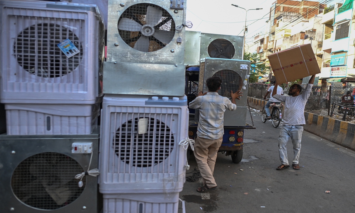People unload air coolers from a delivery truck at a wholesale market amid rising temperatures and heatwave conditions in Allahabad, India, on May 21, 2026. Photo: VCG