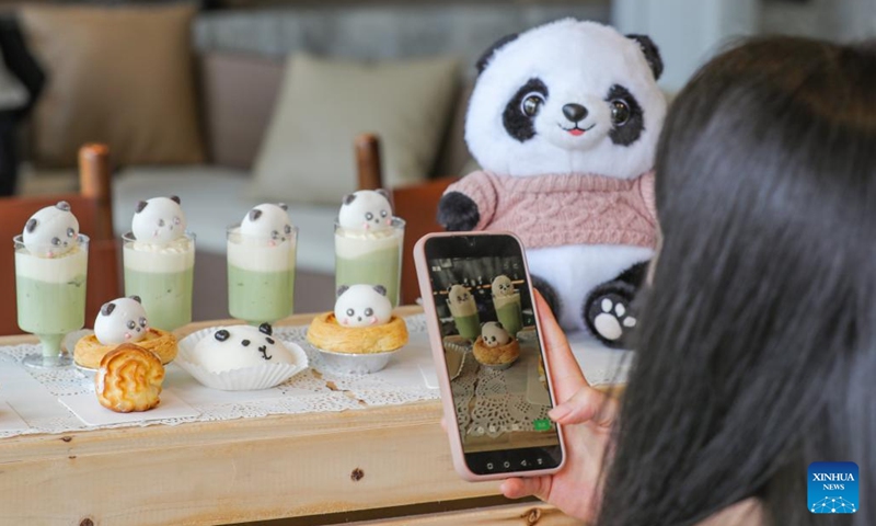 A woman takes photos of sweets at a cafe of the giant panda origin camp in Dengchigou Village of Baoxing County of Ya'an City, southwest China's Sichuan Province, June 2, 2026. The giant panda origin camp, which is composed of three zones offering cultural experience, science popularization and camping, has served as an important base for the promotion and education of giant panda eco-culture. (Photo: Xinhua)