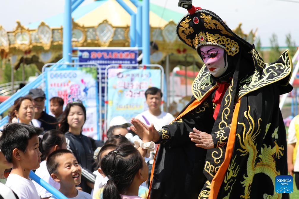 Children watch the performance of bianlian, or face-changing, a stunt of Sichuan Opera, at an amusement park in Zhalantun City of north China's Inner Mongolia Autonomous Region, June 3, 2026. Primary and secondary school students take part in various activities in parks, museums, sports arenas, etc. as they enjoy their first-ever spring break in north China's Inner Mongolia Autonomous Region. (Photo: Xinhua)