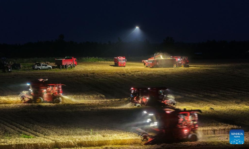A drone photo taken on June 2, 2026 shows agricultural machines harvesting wheat in a field illuminated by a high-power tethered lighting drone in Feidong County, Hefei City, east China's Anhui Province. The wheat harvest season recently started in various places in Anhui Province. On Tuesday night, the Anhui Hefei Power Supply Company under the State Grid dispatched a high-power tethered lighting drone to illuminate the fields of a farm, helping agricultural machinery operators work at night. (Photo: Xinhua)