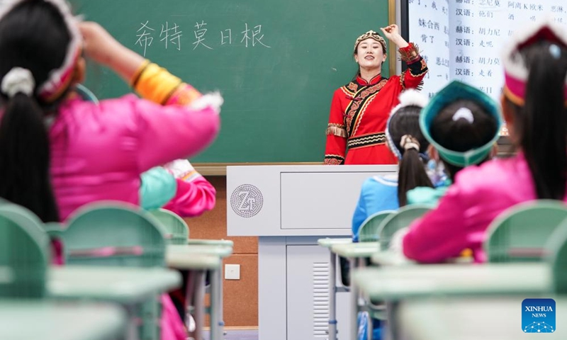 Wu Jing (front), a municipal-level inheritor of Hezhen Yimakan storytelling, teaches students to perform this art at a primary school in Tongjiang City, northeast China's Heilongjiang Province, June 2, 2026. Tongjiang City, home to one of the largest Hezhe communities in China, has stepped up efforts in recent years to safeguard intangible cultural heritage of Hezhe people, including Hezhen Yimakan storytelling, fish-skin craftsmanship, and local fishing and hunting customs. Such efforts aim to help the traditional ethnic culture thrive in modern times. (Photo: Xinhua)