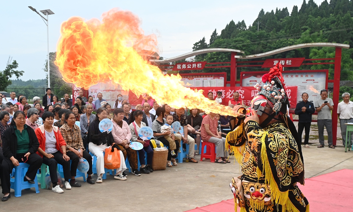 Performers from the Dongxing District Sichuan Opera troupe stage the traditional fire-spitting stunt for local residents in Guixi community, Neijiang, Southwest China's Sichuan Province, on June 3, 2026. Photo: VCG