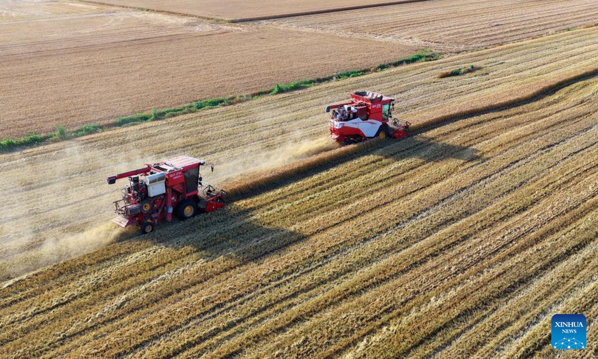An aerial drone photo taken on June 4, 2026 shows reapers harvesting wheat in Sheqi County of Nanyang City, central China's Henan Province. (Photo by Yang Yinpeng/Xinhua)