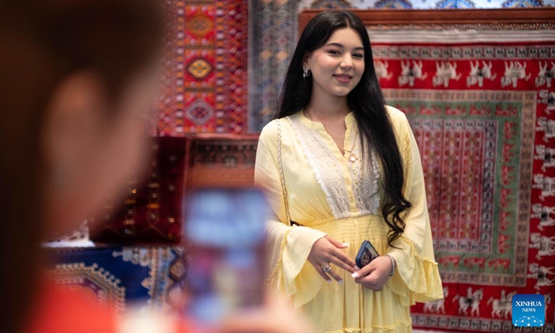 A woman poses for photos at the Turkmen Textile Expo 2026 in Ashgabat, Turkmenistan, June 5, 2026. (Photo by Cui Jiaxin/Xinhua)