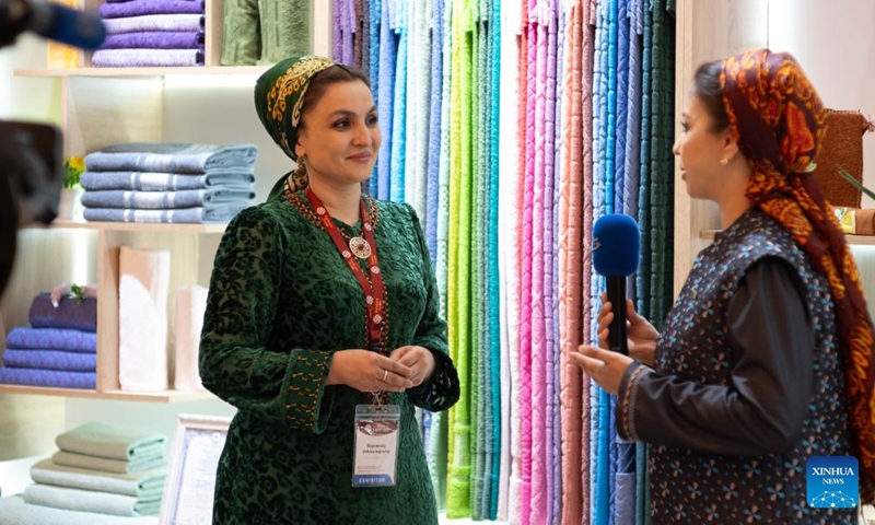 An exhibitor (L) receives an interview by a journalist at the Turkmen Textile Expo 2026 in Ashgabat, Turkmenistan, June 5, 2026. (Photo by Cui Jiaxin/Xinhua)