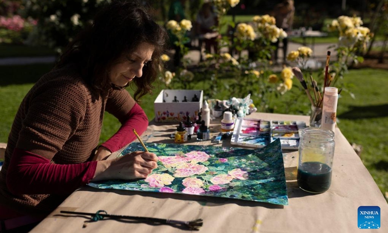 A woman paints roses during a rose display event at the Volcji Potok Arboretum near Kamnik, Slovenia, June 6, 2026. (Photo by Zeljko Stevanic/Xinhua)