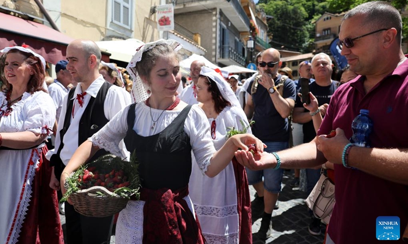 A local woman in traditional costumes offers complimentary strawberries to a tourist at 2026 Nemi Strawberry Festival in Nemi, Lazio, Italy, June 7, 2026. (Xinhua/Li Jing)
