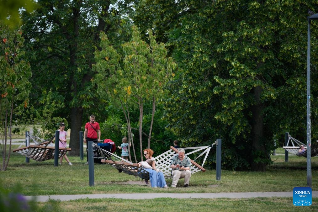 People relax in a park in Warsaw, Poland, June 9, 2026. Warsaw experienced a sharp weather change on Tuesday as temperature rose high in the afternoon before rain and cold air caused a rapid temperature drop. (Photo: Xinhua)