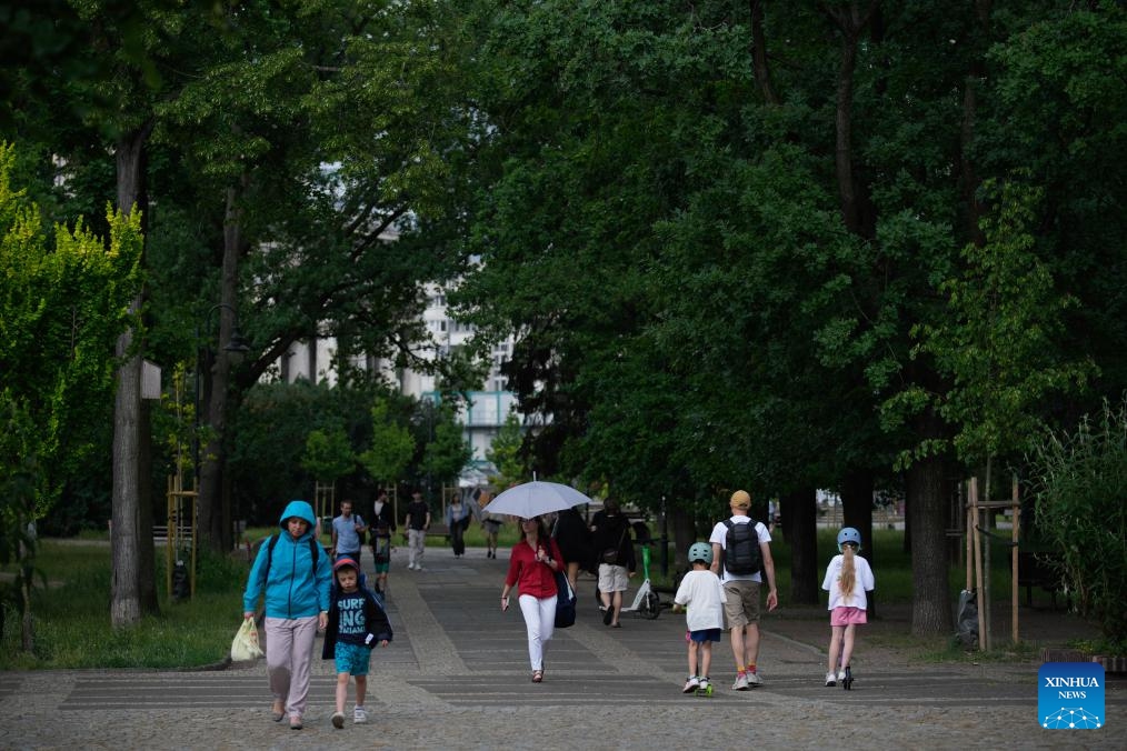People walk in a park in Warsaw, Poland, June 9, 2026. Warsaw experienced a sharp weather change on Tuesday as temperature rose high in the afternoon before rain and cold air caused a rapid temperature drop. (Photo: Xinhua)