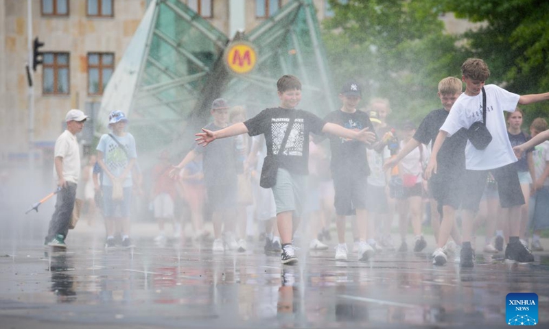 Children walk through cooling mist in Warsaw, Poland, June 9, 2026. Warsaw experienced a sharp weather change on Tuesday as temperature rose high in the afternoon before rain and cold air caused a rapid temperature drop. (Photo: Xinhua)