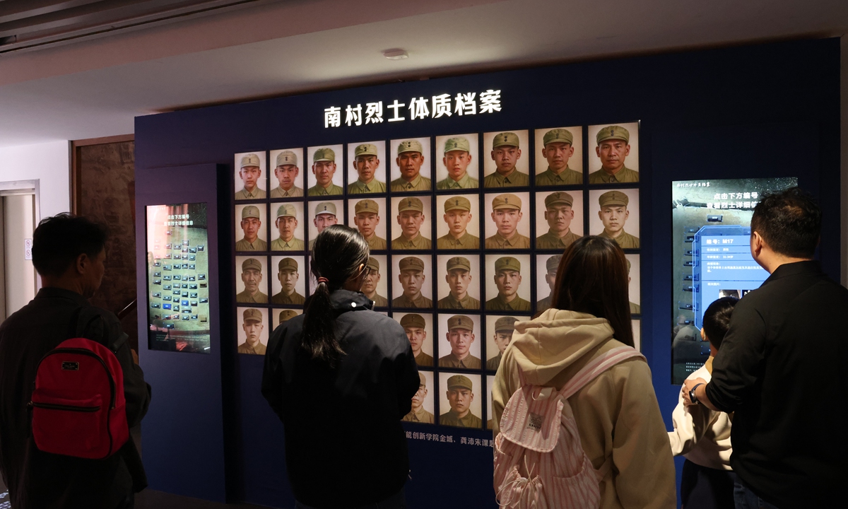Visitors look at a board showing the portraits of martyrs at an exhibition in Shanghai. Photo: VCG