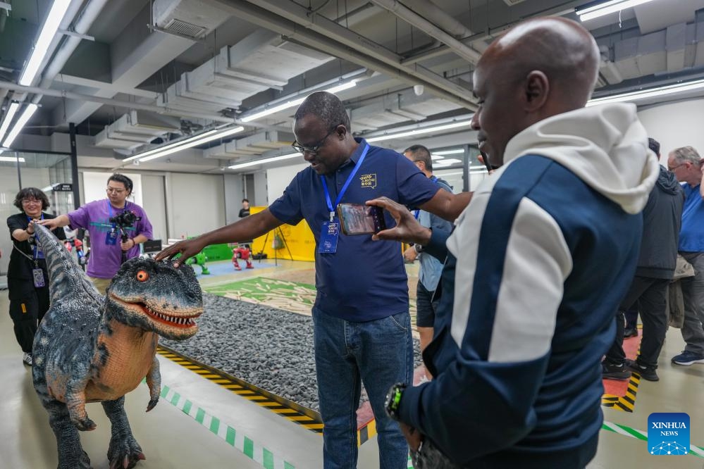 Members of a multinational delegation interact with an intelligent dinosaur robot at Chengdu Humanoid Robot Innovation Center in Chengdu, southwest China's Sichuan Province, June 8, 2026. Delegates from 11 countries visited livelihood projects on ecological conservation, cultural and creative industries, and scientific and technological innovation in Sichuan from June 7 to 9. They learned on-site about how China's development has improved people's livelihood. (Photo: Xinhua)