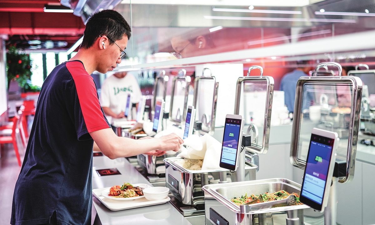 A diner fetches his meal with digital devices tallying the total cost and providing a summary of total nutritional intake at checkout at a canteen in Beijing on May 14, 2026. Photos on this page: VCG