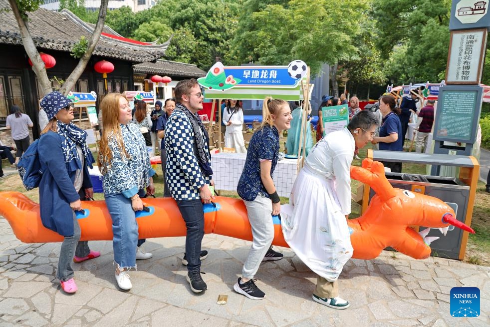 A staff member (1st R) and foreigners participate in a land dragon boat activity during a cultural exchange event in Nantong, east China's Jiangsu Province, on June 11, 2026.
A cultural exchange event was held at the Nantong Blue Calico Museum on Thursday. A series of activities enables foreign friends to learn about the blue calico printing and dyeing craft and dragon-boat festival customs. (Photo by Xu Congjun/Xinhua)