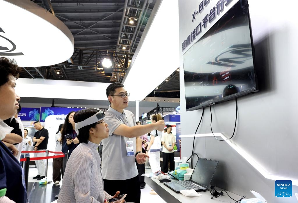 A staff member (R) introduces a wearable brain-computer interface (BCI) device to a visitor during the 12th China (Shanghai) International Technology Fair (CSITF) in east China's Shanghai, June 11, 2026. The 12th China (Shanghai) International Technology Fair, scheduled from June 11 to 13, kicked off at the Shanghai World Expo Exhibition and Convention Center on Thursday. The fair covers an exhibition area of about 38,000 square meters, showcasing innovative technological achievements in fields including artificial intelligence, green fuels, energy storage and transportation, smart home application and elderly care. (Xinhua/Fang Zhe)