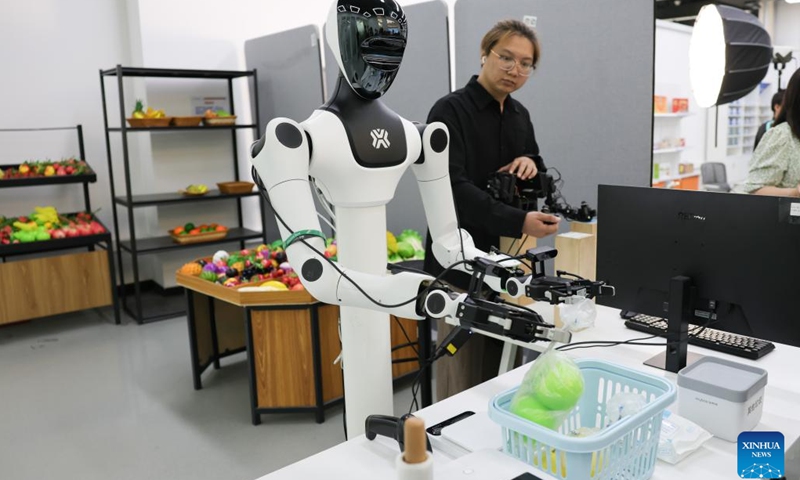 A staff member collects data on a robot's movements as it works under a supermarket scenario at the embodied intelligence robot data and training base of the Beijing Innovation Center of Humanoid Robotics in Beijing, capital of China, June 12, 2026.

