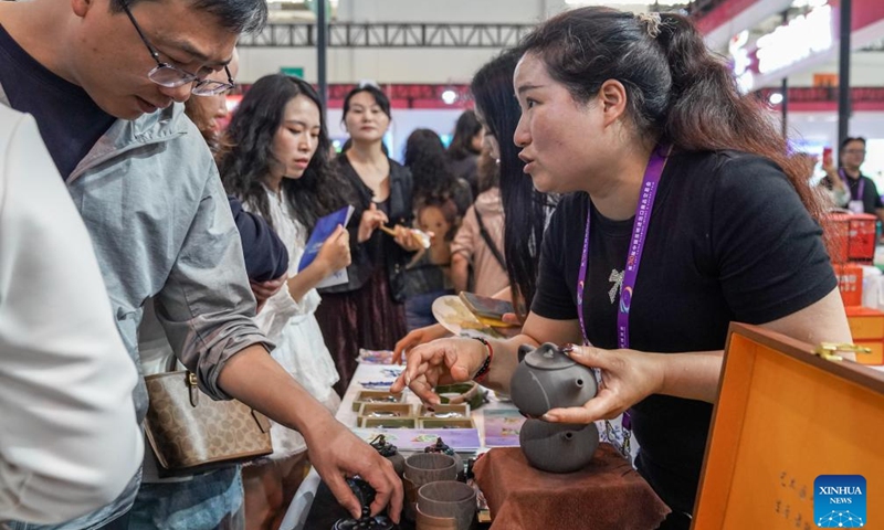 A visitor learns about purple clay teapots at the 10th China-South Asia Expo in Kunming, southwest China's Yunnan Province, June 13, 2026. The China-South Asia Expo, runs from June 11 to 16 in Kunming of Yunnan Province. A variety of local specialty products displayed at the expo enables visitors to gain a better understanding of Yunnan Province. (Xinhua/Peng Yikai)